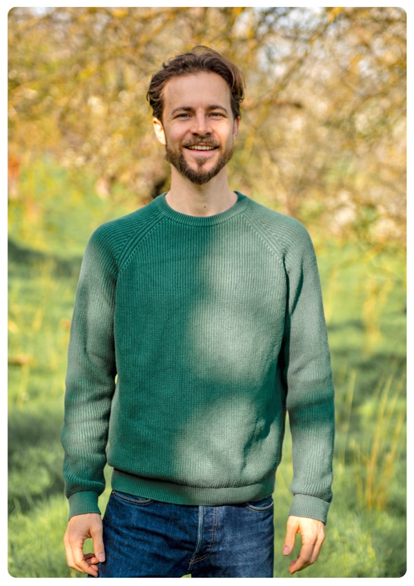 Heilpraktiker Lennart Franke im grünen Pulli auf einer Wiese.